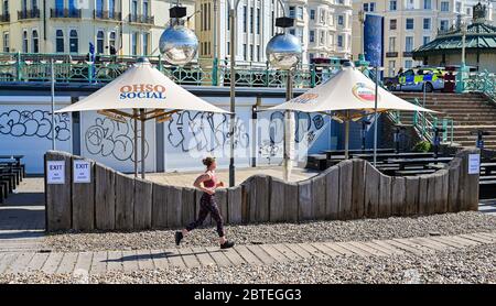 Brighton UK 25 maggio 2020 - UN corridore gode il sole caldo bello sulla spiaggia di Brighton presto oggi come la folla si aspetta che si radunino ai punti di bellezza e alle spiagge intorno al paese durante le feste di banca come le temperature sono previste per raggiungere gli alti 20 nel sud-est dell'Inghilterra Durante la crisi pandemica del Coronavirus COVID-19 . Credit: Simon Dack / Alamy Live News Foto Stock