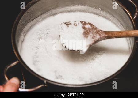 Lavorazione del formaggio fresco, formaggio a grumi in padella, cotone fatto in casa, formaggio a pasta di ricci o paneer Foto Stock