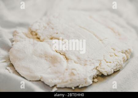 Lavorazione del formaggio fresco, formaggio di cottage o paneer su tela di cotone, fatto in casa Foto Stock