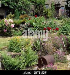 Rullo da giardino in ferro d'epoca appoggiato su un muro di pietra Foto Stock