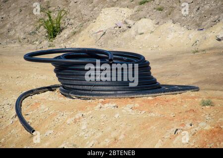 Un tubo di plastica arrotolato nella baia. Posa di un tubo idraulico. Foto Stock