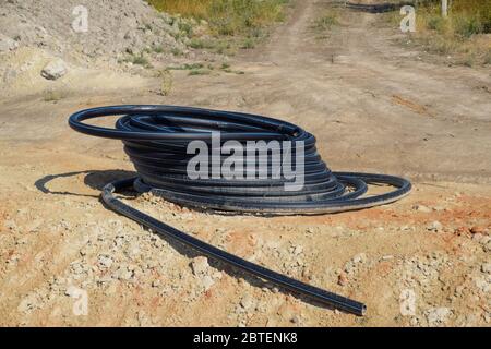 Un tubo di plastica arrotolato nella baia. Posa di un tubo idraulico. Foto Stock