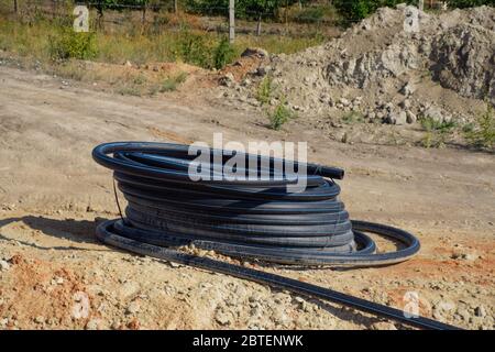 Un tubo di plastica arrotolato nella baia. Posa di un tubo idraulico. Foto Stock