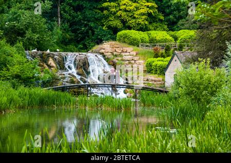 Un giovane su un ponte di fronte al Grand Cascades nei giardini del Palazzo di Blenheim, Oxfordshire, Inghilterra. Foto Stock