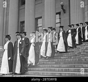 Studenti di sesso femminile che camminano giù i gradini in caps e camici - Barnard College Graduation ca. 1913 Foto Stock