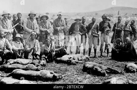 Uomo d'affari, cacciatore e filantropo Paul James Rainey (1877-1923) e uomini africani con animali morti (leoni?) In Africa ca. 1910-1915 Foto Stock