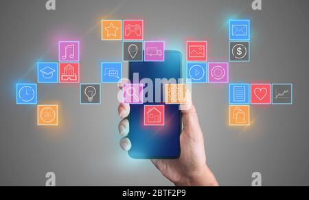 Mano femminile che tiene lo smartphone su sfondo grigio, collage con icone funzionali per i dispositivi mobili Foto Stock