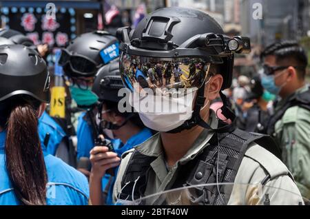 Un poliziotto si guarda mentre indossa una maschera facciale come misura preventiva presso la zona di Causeway Bay durante la protesta. Violenza, Arresti e uso di cannoni ad acqua tornarono nelle strade di Hong Kong con centinaia di manifestanti che marciavano sull'isola di Hong Kong contro i piani della Cina di imporre una legge nazionale sulla sicurezza. Foto Stock