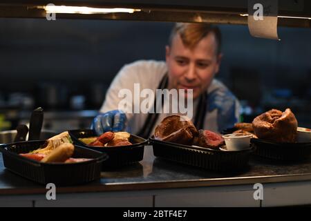 Lo chef Stuart McAlney serve cene take away arrosto al pub Crabtree di Fulham, Londra, dopo l'introduzione di misure per portare il paese fuori dalla serratura. Foto Stock