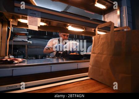 Lo chef Stuart McAlney serve cene take away arrosto al pub Crabtree di Fulham, Londra, dopo l'introduzione di misure per portare il paese fuori dalla serratura. Foto Stock