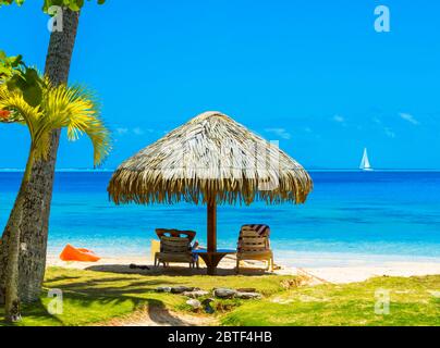 Royal Huahine, Huahine, Polinesia francese 24 settembre. 2018: Ombrello di paglia sulla spiaggia nella Laguna Huahine, acqua turchese cristallina Foto Stock