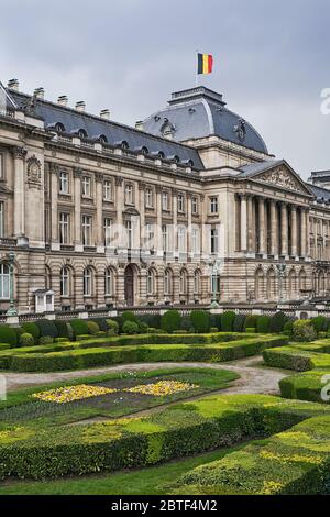 Il Palazzo reale di Bruxelles, Belgio, dall'angolo nord-orientale in primavera. Bandiera nazionale del Regno del Belgio che sventola in cima. Foto Stock