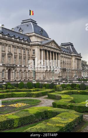 Il Palazzo reale di Bruxelles, Belgio, dall'angolo nord-orientale in primavera. Bandiera nazionale del Regno del Belgio che sventola in cima. Foto Stock