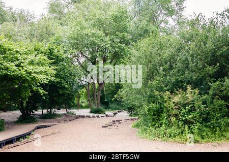 Area giochi per bambini, bambini che si godono una bella giornata primaverile, con i cieli blu gloriosi nel Parco di Morden Hall Foto Stock