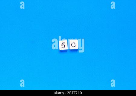 5 G. cinque G, scritte in lettere di legno su sfondo blu. Layout piatto. Rete wireless. Nuova tecnologia. Vista dall'alto. Foto Stock