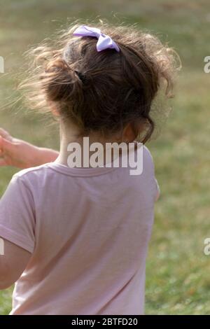 una vista ravvicinata di una bambina con un arco viola nei capelli Foto Stock