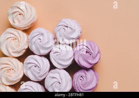 Quattro marshmallows su sfondo pastello. zephyr o marshmallow giallo dolce fatto in casa. Disposizione piatta. Vista dall'alto Foto Stock