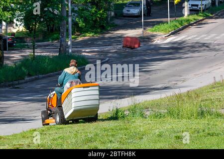 Un addetto alle utenze si occupa dei prati lungo la strada, falciando erba alta con un rasaerba professionale, immagine con spazio per la copia. Foto Stock