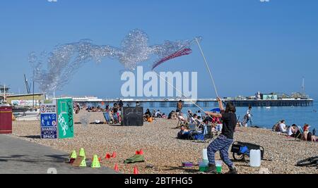 Brighton UK 25 maggio 2020 - UN animatore di bolle nel tardo pomeriggio sole sulla spiaggia e sul lungomare di Brighton, come il fine settimana di festa della banca si avvicina oggi alla fine sulla costa meridionale durante la crisi pandemica di Coronavirus COVID-19 . Credit: Simon Dack / Alamy Live News Foto Stock