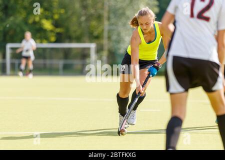 Il giocatore femminile di hockey di campo conduce la palla in attacco nel gioco Foto Stock