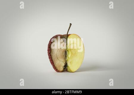 mela rossa con mezzo buono e l'altro mezzo marcio, concetto di tempo, frutta che diventa spazzatura e che viene gettato via, sfondo bianco, isolare Foto Stock