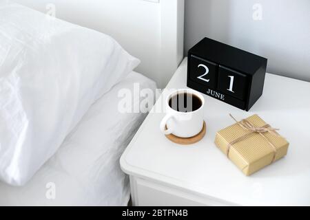 Tazza di caffè del mattino, regalo, calendario di legno nero sul comodino nel giorno felice dei Padri. Concetto di vacanza Foto Stock