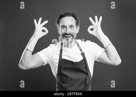 Pulizia eccellente. Ragazzo con bearded che pulisce a casa. Lavoratore con bearded. A protezione della pulizia. Servizio di pulizia e servizio domestico. Molto lavoro. Uomo in grembiule con guanti per la pulizia. Giorno di pulizia oggi. Foto Stock