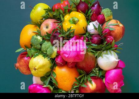 Una composizione colorata sorprendente di una varietà di frutta e verdura fresche, peonie rosa e foglie verdi su sfondo verde Foto Stock