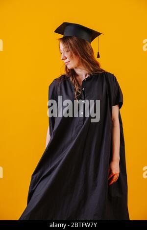 Donna in abito graduato e cappello su sfondo arancione. Foto Stock