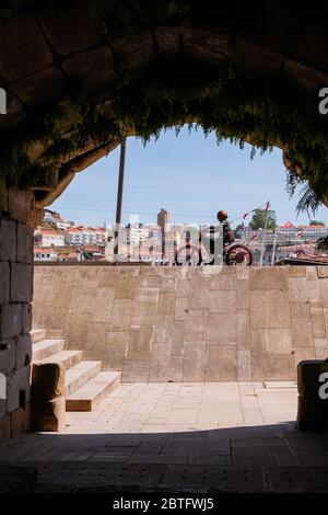 Vista da un tunnel - UN uomo che gira in bicicletta nel quartiere Ribeira di Porto, Portogallo Foto Stock