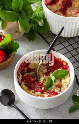 Primo piano con dessert estivo fatti in casa. Le fragole si sbriciolano in teglia su un piano in pietra o ardesia. Foto Stock