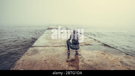 Fotografo su un molo in cemento scatta una foto di un mare foggoso. Foto Stock