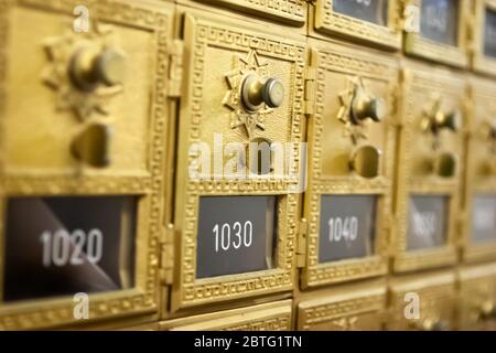 Fila di caselle postali vintage in ottone con porte e serrature combinate in una sala postale. Foto Stock