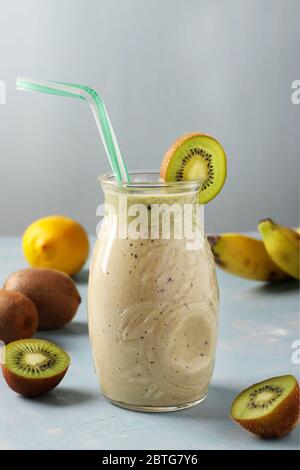 Sano disintossicazione frullato kiwi, banana, limone in vaso di vetro su sfondo azzurro con ingredienti freschi, dieta e controllo della perdita di peso concetto, Closeup Foto Stock