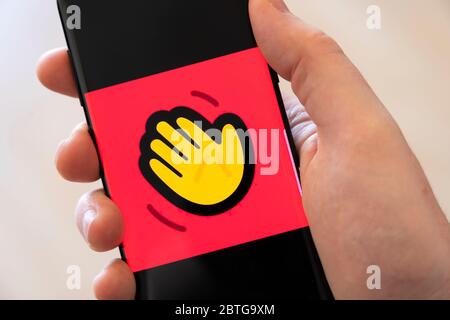 Una mano di un uomo che tiene uno smartphone con un grande logo per l'applicazione di videochiamata Housseparty Foto Stock