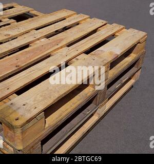Pallet usati in legno giacenti sul pavimento in asfalto in condizioni di sole all'aperto, primo piano Foto Stock