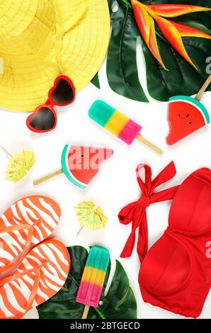 Resort vacanze estive a tema con cappello, gelati, costume da bagno, occhiali da sole, foglie tropicali e fiori in colori luminosi. Moderno ed elegante Foto Stock