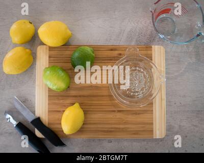 Utilizzando una centrifuga a mano in vetro e uno zester, estrarre il succo e macinare i limoni e i lime per una ricetta Foto Stock