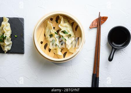 Primo piano gnocchi di gyoza bolliti freschi in legno di bambù vaporiera con salsa di soia vista dall'alto. Foto Stock