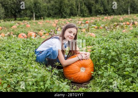 Carina bambina con zucca enorme in un tegolo di zucca. Foto Stock