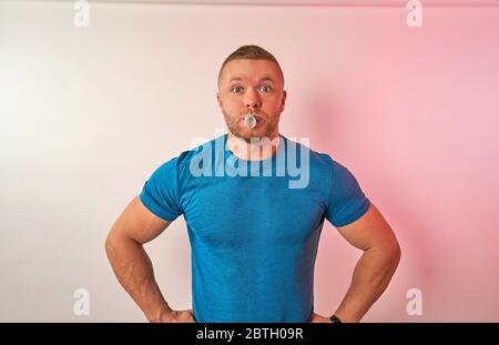 un uomo con gomma da masticare in bocca su uno sfondo chiaro Foto Stock