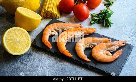 Gamberi gamberetti spaghetti italiani, menta fresca, pomodoro, limoni ardesia sfondo con Copy Space. Vista laterale primo piano Foto Stock