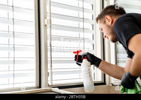 Un primo piano di una pulizia professionale tende finestra in un appartamento con un panno in microfibra verde Foto Stock