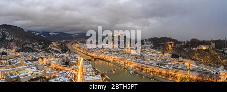 Volo panoramico in drone aereo di Salisburgo innevata all'ora del tramonto in inverno Foto Stock