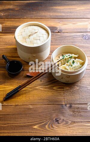 Gnocchi gyoza freschi bolliti in vaporiera di legno con salsa di soia chissos cucina cinese tradizionale vista laterale. Foto Stock