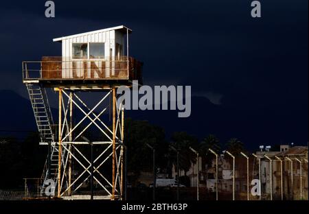 Nicosia, Cipro - 12 febbraio 2020: Una torre di guardia delle Nazioni Unite intemperie illuminata dal sole con nubi oscure tuose sullo sfondo. Foto Stock