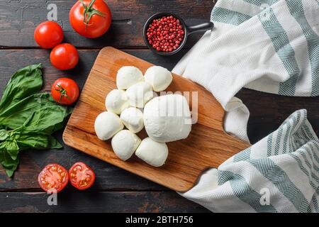 Ingredienti insalata caprese pomodoro e mozzarella con basilico ed erbe su vecchio tavolo fattoria in legno d'epoca stile biologico vista dall'alto. Foto Stock