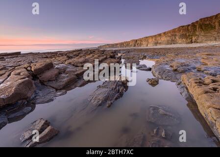 Piscina di roccia calma alla spiaggia di Nash Point, Galles del sud, al tramonto Foto Stock