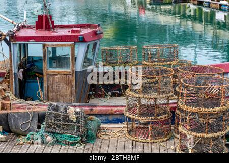 un vecchio stile di pesca costiera in banchine sul porto con pentole di aragosta e granchio pronte per il caricamento sui ponti. Foto Stock