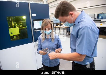 Ditzingen, Germania. 26 Maggio 2020. I dipendenti della società di ingegneria meccanica Trumpf stanno esaminando una lamiera accanto a una macchina da taglio laser nel centro dimostrativo dell'azienda. Indossano una maschera sulla bocca e sul naso. (A dpa 'l'ingegneria meccanica nel sud-ovest disegna il primo equilibrio corona') Credit: Marijan Murat/dpa/Alamy Live News Foto Stock